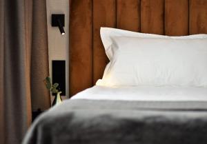 a bed with a white pillow and a wooden headboard at Patio Riverfront in Gdańsk
