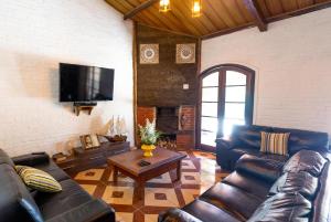 - un salon avec des canapés en cuir et une télévision dans l'établissement Garden House Pousada, Boutique & Spa, à São Roque