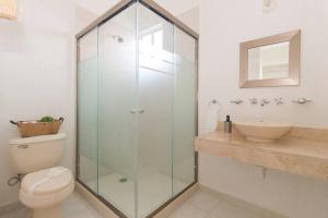 a bathroom with a glass shower with a toilet and a sink at Casa Bella in Playa del Carmen +18 photos