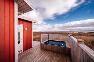 a hot tub on a deck next to a red building at Blue View Cabin 1B With private hot tub in Reykholt