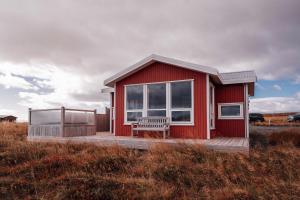 ein rotes Haus mit einer Bank auf einem Feld in der Unterkunft Blue View Cabin 1A With private hot tub in Reykholt