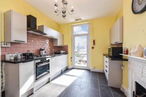 cocina con paredes amarillas y armarios blancos en Traditional 3-Bed Property in Pontcanna with Parking, en Cardiff