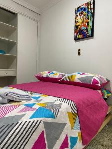 a bedroom with a bed with a colorful quilt on it at Hostel Kumho alojamiento in Medellín