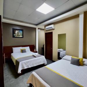 a hotel room with two beds and a mirror at Hotel - Bravo Grand Hotel in Quevedo