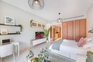 a white bedroom with a bed and a desk at Central studio in The Greens 10min to MetroStation in Dubai