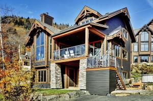 a large house with a porch and a balcony at Chalet 27 Chemin Blanc by Les Chalets Alpins in Stoneham