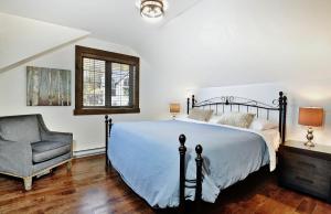 a bedroom with a bed and a chair at Chalet 27 Chemin Blanc by Les Chalets Alpins in Stoneham