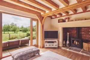 a living room with a fireplace and a tv at Apple Tree Cottage in Beckford