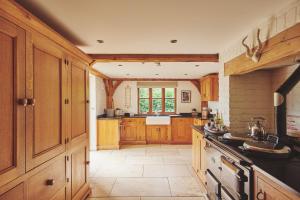 a kitchen with wooden cabinets and a stove top oven at Apple Tree Cottage in Beckford