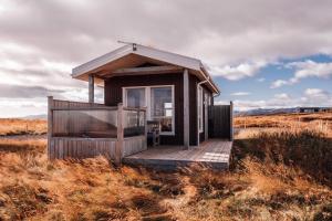 una pequeña cabaña en medio de un campo en Blue View Cabin 5B With private hot tub, en Reykholt