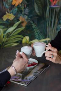 twee mensen met koffiekopjes aan een tafel bij Garni hotel BARUT in Šabac