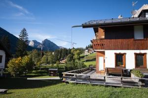 een houten huis met een veranda en bergen op de achtergrond bij Casa Chiave in Cortina dʼAmpezzo