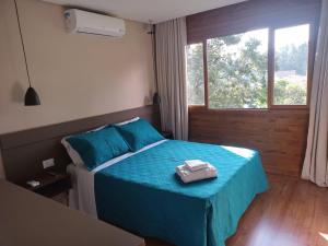 Schlafzimmer mit einem Bett mit blauer Bettwäsche und einem Fenster in der Unterkunft Pousada São Chico Eco Village in São Francisco de Paula