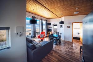 uma sala de estar com um sofá e uma sala de jantar em Blue View Cabin 3A With private hot tub em Reykholt