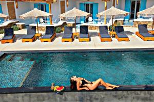 una donna sdraiata sul bordo di una piscina di Ethereal Apartments ad Agrari