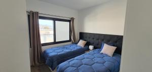 a bedroom with a blue bed and a window at Apartamento T2-5m Aeroporto CR7 in Santa Cruz +28 photos