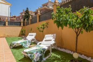 Tres sillas de jardín y un árbol en un patio en Villa Ca'n Serra, en Cájar
