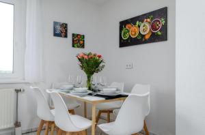 een witte eetkamer met een tafel en witte stoelen bij JeyFL Apartments: Zentral - stilvoll - komfortabel in Maagdenburg