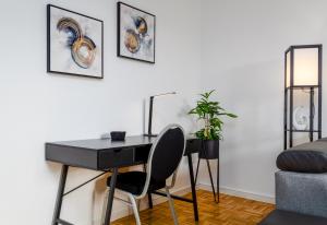 einen Schreibtisch in einem Zimmer mit einem Bett und einer Pflanze in der Unterkunft JeyFL Apartments: Zentral - stilvoll - komfortabel in Magdeburg