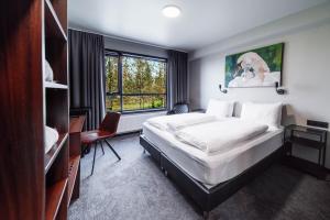 Schlafzimmer mit einem Bett, einem Schreibtisch und einem Fenster in der Unterkunft Blue Hotel Fagrilundur - On The Golden Circle in Reykholt