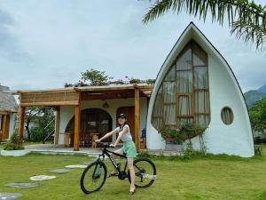 a woman riding a bike in front of a house at Bavi Myan Maison in Yên Cư