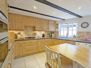 a kitchen with wooden cabinets and a wooden table at Baytree Cottage, Walberton in Walberton