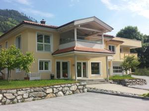a large yellow house with a stone wall at Haus 4 Holidays in Bramberg am Wildkogel