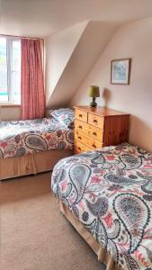 a attic bedroom with two beds and a dresser at 26 Castle Street in Kirkcudbright