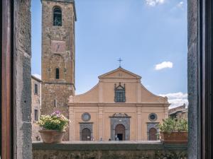 una chiesa con una torre dell'orologio e due piante in vaso di Locanda Della Buona Ventura a Bagnoregio