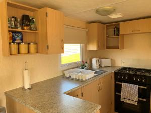 a kitchen with wooden cabinets and a stove and a sink at Loch Heron View in Newton Stewart