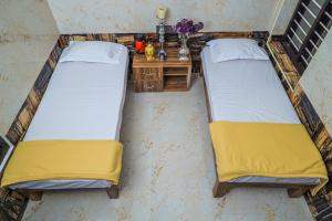 two beds in a room with a nightstand and a table at Royal Lodge in Nāgercoil