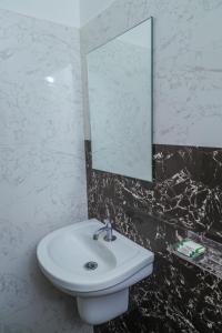 y baño con lavabo blanco y espejo. en Royal Lodge, en Nāgercoil