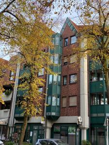 un edificio alto de ladrillo con árboles delante de él en Hüls Central Apartment, en Marl