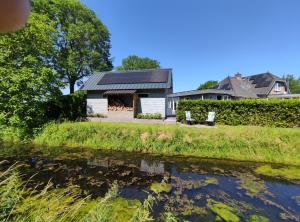 uma casa com um rio em frente em B&B Het Zwanennest em Lienden