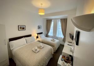 una camera d'albergo con due letti e una televisione di The Gateway Hotel a Londra