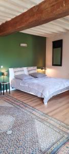 a large bed in a bedroom with a green wall at La Petardière in Meaux