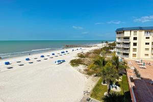 a beach with umbrellas and a building and the ocean at Beach Cottage 1405 in Clearwater Beach