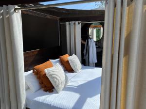 a bed with orange and white pillows in a tent at Sierra Salvada Bubbles in Salmantón