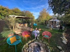 a woman sitting in a yard with chairs and a fire pit at Stamford Meadows Glamping with Private Hot Tubs in Stamford