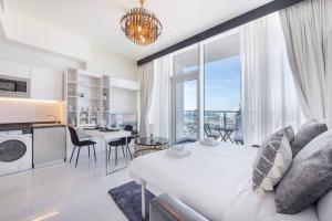 a living room with a large white bed and a kitchen at Breathtaking view compact & modern spacious studio in Dubai