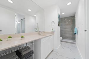 a white bathroom with a sink and a shower at Extraordinary Oceanfront Condo - Heated Pool, Gym and Game Room - Hollywood Beach in Hollywood