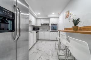 a kitchen with white cabinets and a stainless steel refrigerator at Extraordinary Oceanfront Condo - Heated Pool, Gym and Game Room - Hollywood Beach in Hollywood