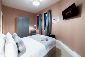 a bedroom with a white bed and a tv on the wall at (Kensington Museum) 2 bedroom apartment London in London