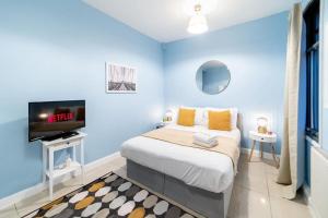 a blue bedroom with a bed and a tv at (Kensington Museum) 2 bedroom apartment London in London