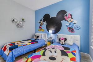a bedroom with two beds and a mural of mickey mouse at Oasis at Solterra - 5 bed family resort pool home in Davenport