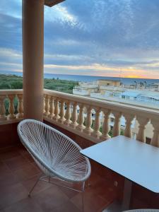 a white chair and a table on a balcony with the ocean at Hotel Vent de Mar in Puerto de Sagunto