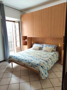 Schlafzimmer mit einem großen Bett mit einem Kopfteil aus Holz in der Unterkunft Bilocale Vecchio Borgo in Borgosesia
