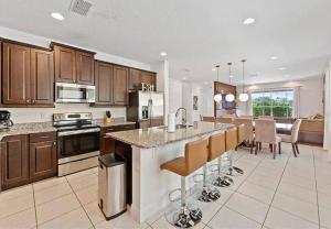 a kitchen with wooden cabinets and a kitchen island with bar chairs at 371 P Luxury Villa- New Listing in Orlando
