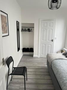 um quarto com uma cama, uma cadeira e uma porta em Cheerful 5 Bedrooms & En-Suite Bathrooms Town House em Northampton