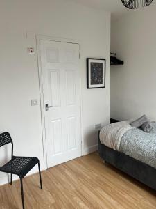 a bedroom with a bed and a chair and a door at Cheerful 5 Bedrooms & En-Suite Bathrooms Town House in Northampton